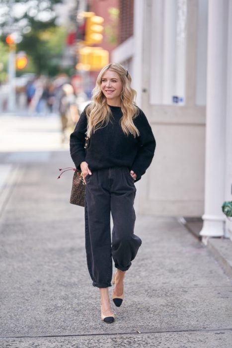 chica rubia con sueter negro, jeans slouchy negros y flats