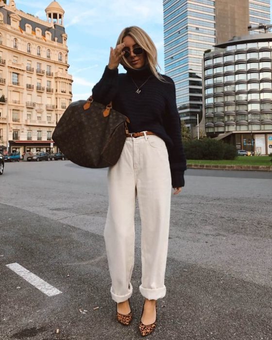 chica rubia con lentes de sol, suéter negro, bolso oversized y pantalones slouchy color crema