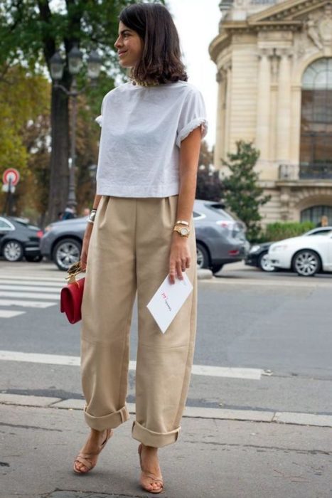 chica de cabello castaño con playera blanca, bolso negro y pantalones slouchy color beige