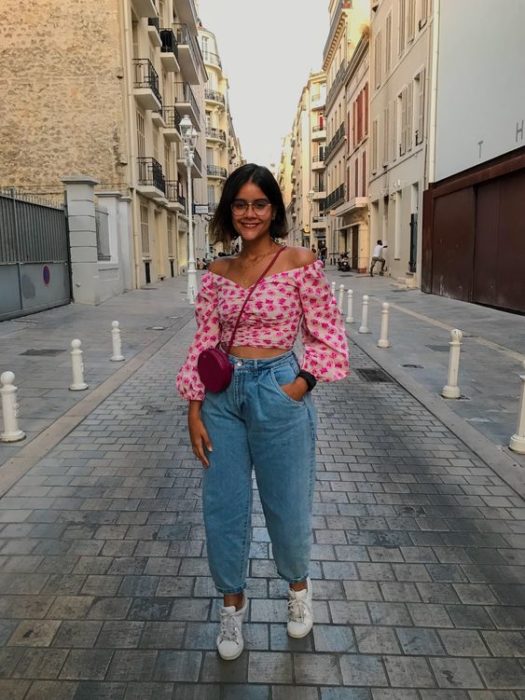 chica de cabello corto con blusa rosa de lunares, bolso rojo, jeans slouchy y tenis