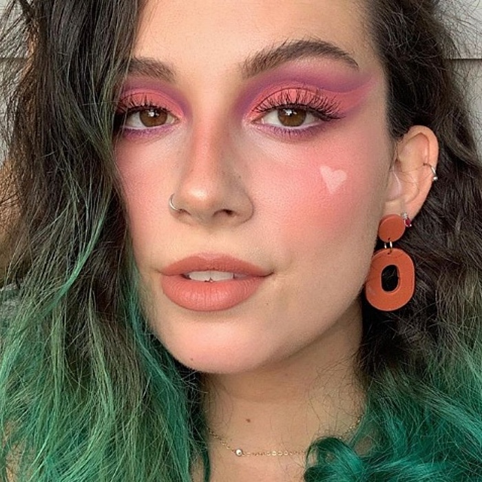 chica con cabello teñido verde, usando maquillaje en colores rosa pastel