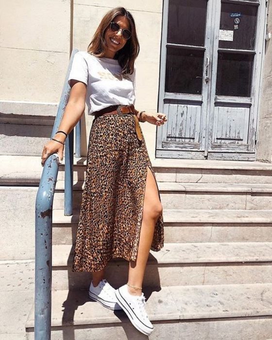 chica con camiseta blanca, falda midi con animal print y tenis deportivmos, cabello castaño