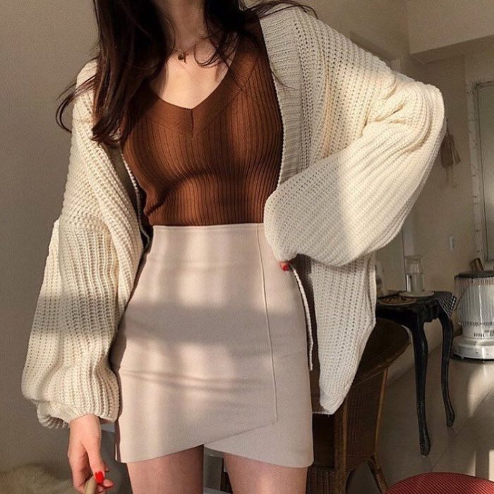 chica con falda beige, blusa cafe y suéter tejido