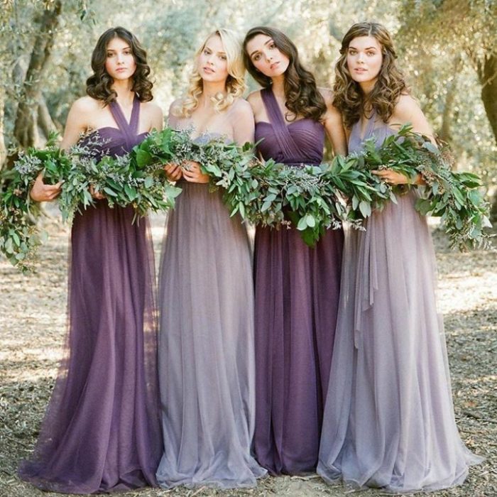 damas de honor usando vestidos de gasa largos en colores morado y lila oscuro