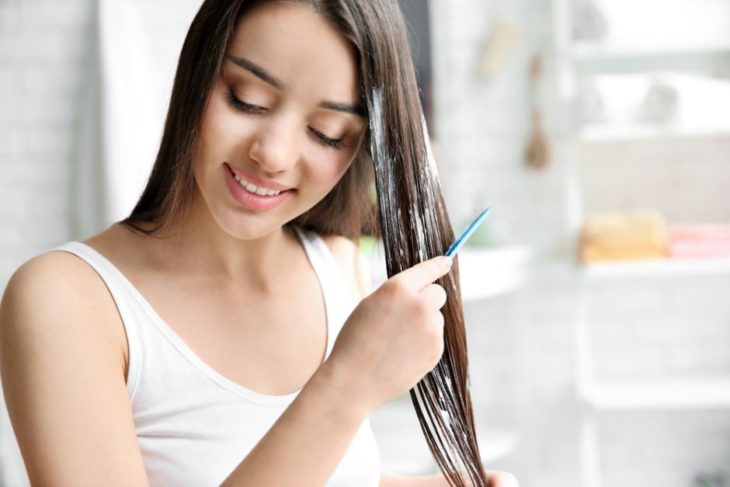 Chica aplicando mascarilla capilar sobre su cabello húmedo