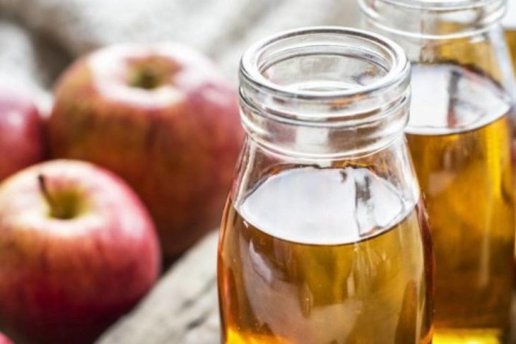 Botellas de vidrio con vinagre de manzana en el interior