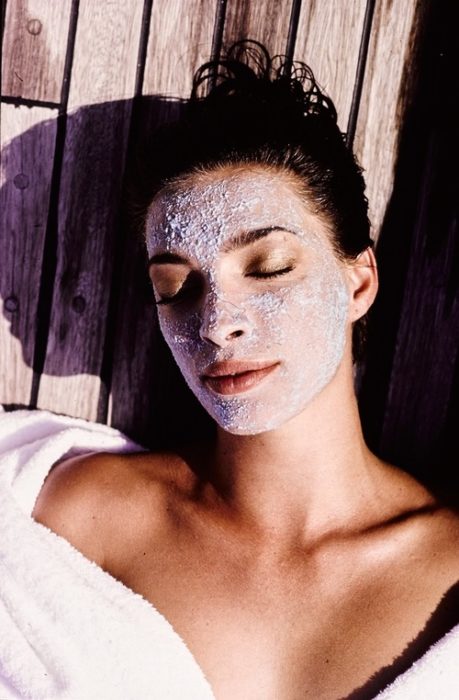 Chica tomando el sol llevando una mascarilla con grenetina