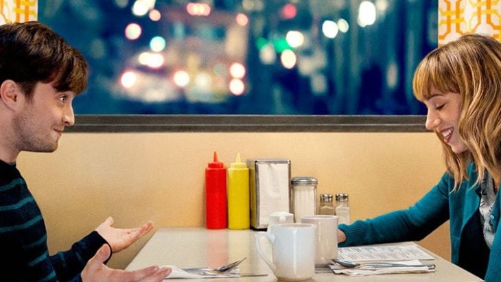 Daniel Radcliffe en la película sentado en una cafetería junto a una chica