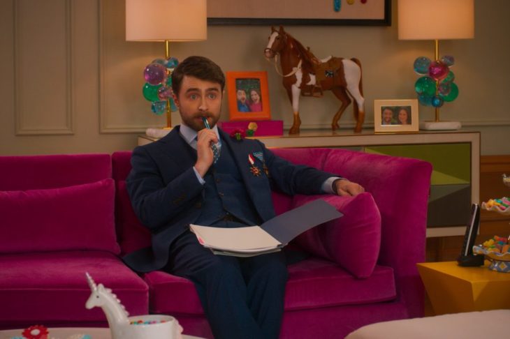 Daniel Radcliffe en la película Unbreakable Kimmy Schmidt: Kimmy contra el reverendo, sentado en un sofá rosa