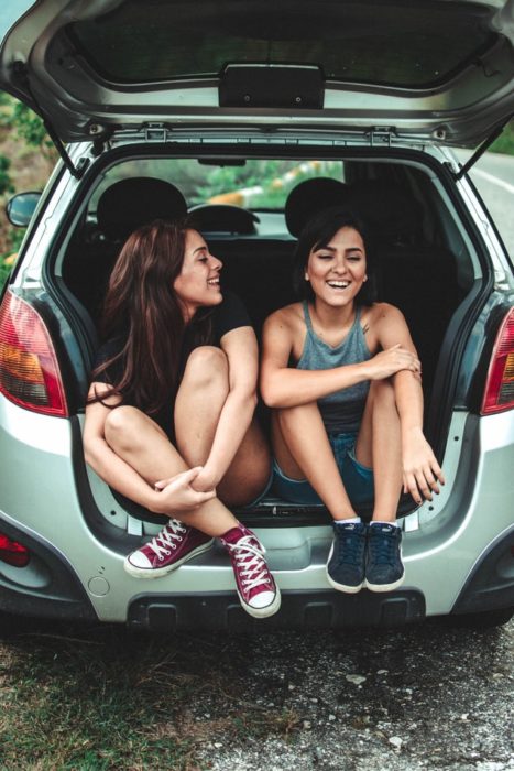 Amigas dentro de un coche sonriendo y charlando