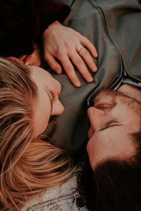 Pareja de novios recostados, mirándose a los ojos y sonriendo