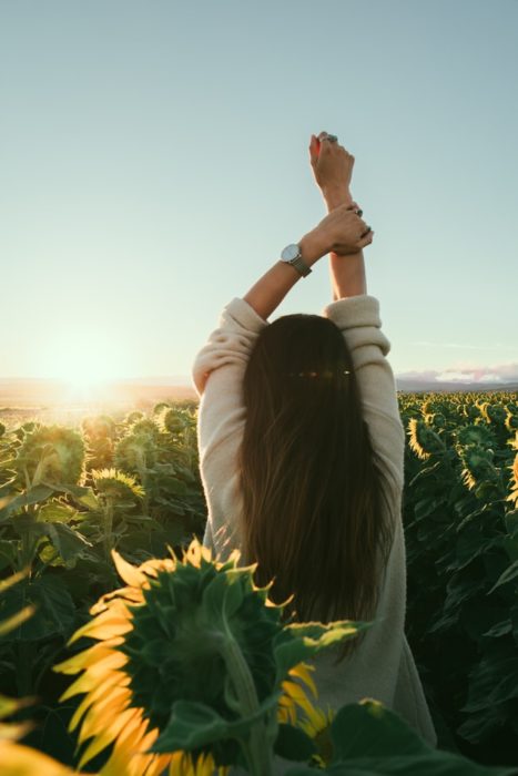 Chica de espaldas mirando un campo de girasoles