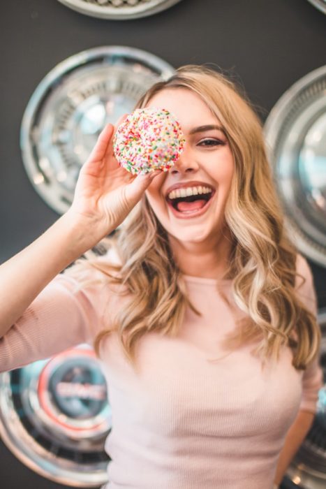 Chica sonriendo y jugando con una rosquilla