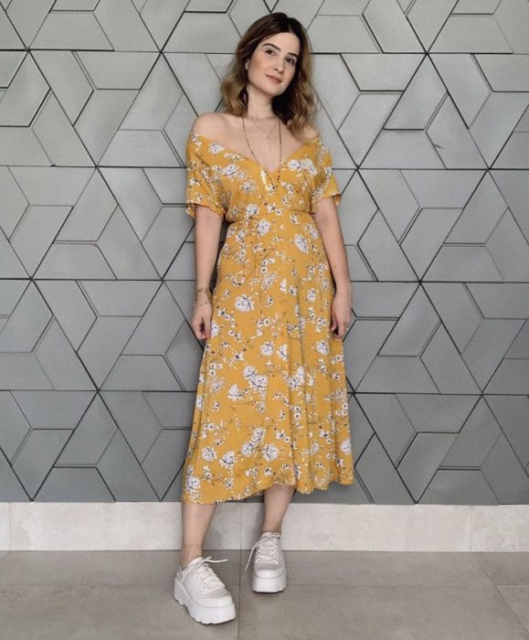 Chica usando vestido midi color amarillo y tenis blancos