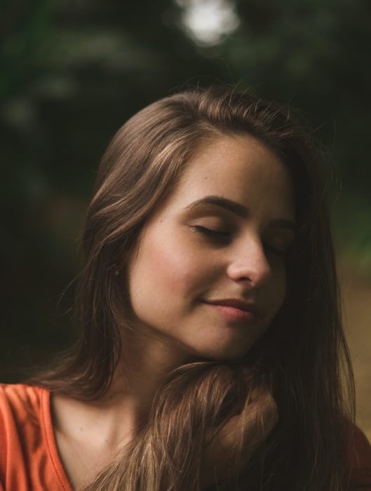 Chica con los ojos cerrados y sonriéndo