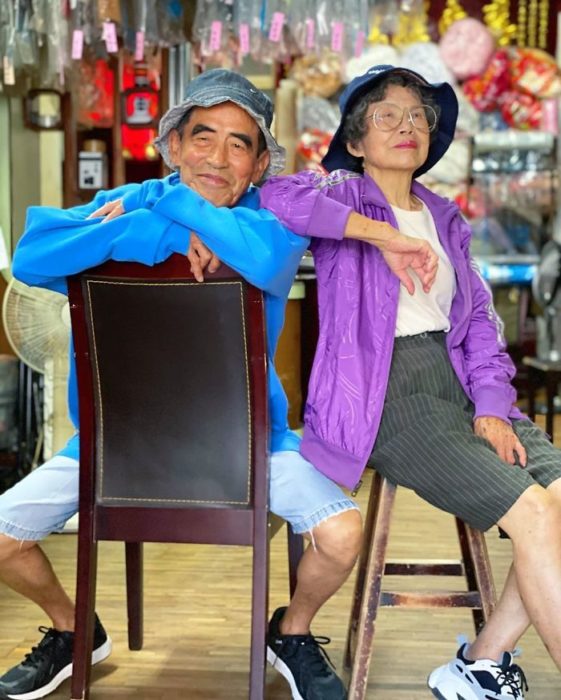 Pareja de abuelitos sentados en bancos de madera llevando sombreros estilo pescador a juego