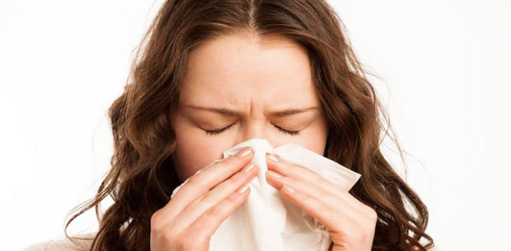 Chica alérgica estornudando con un pañuelo