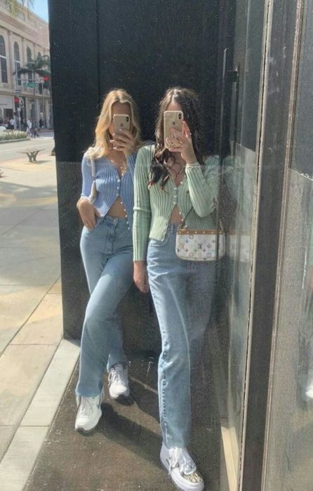 Mejores amigas con outfits iguales de suéter color pastel y jeans