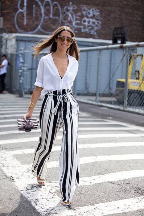 Chica usando una blusa de color blanco con pantalón de rayas y bolso negro