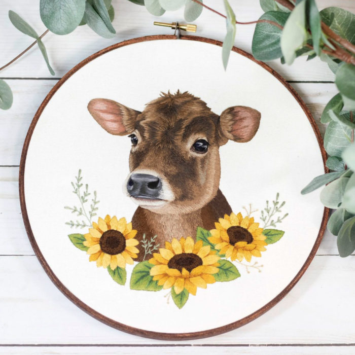 Artista Michelle Staub hace bordados de mascotas; bordado de vaca café con manchas blancas y girasoles