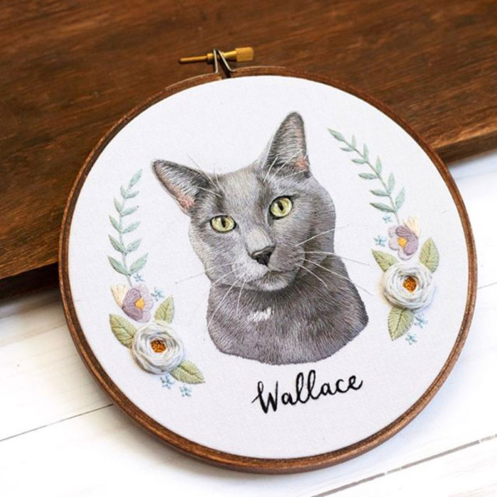 Artista Michelle Staub hace bordados de mascotas; bordado de gato gris con manchas blancas, nariz negra y ojos verdes, con flores