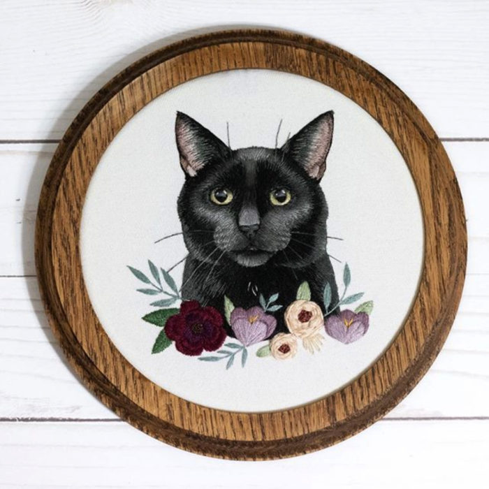 Artista Michelle Staub hace bordados de mascotas; bordado de gato negro con ojos verdes, flores rojas, moradas y blancas