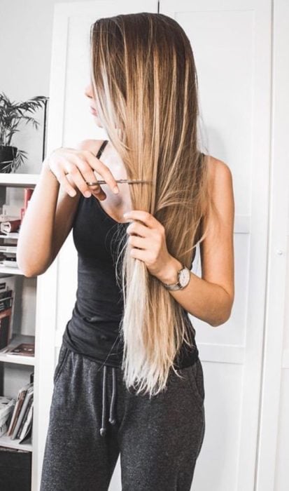 Chica cortando su cabello largo