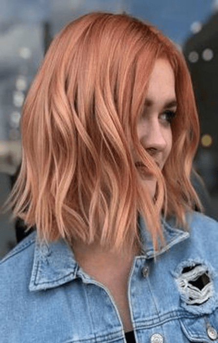 Chica mostrando cu cabello teñido en peachy copper