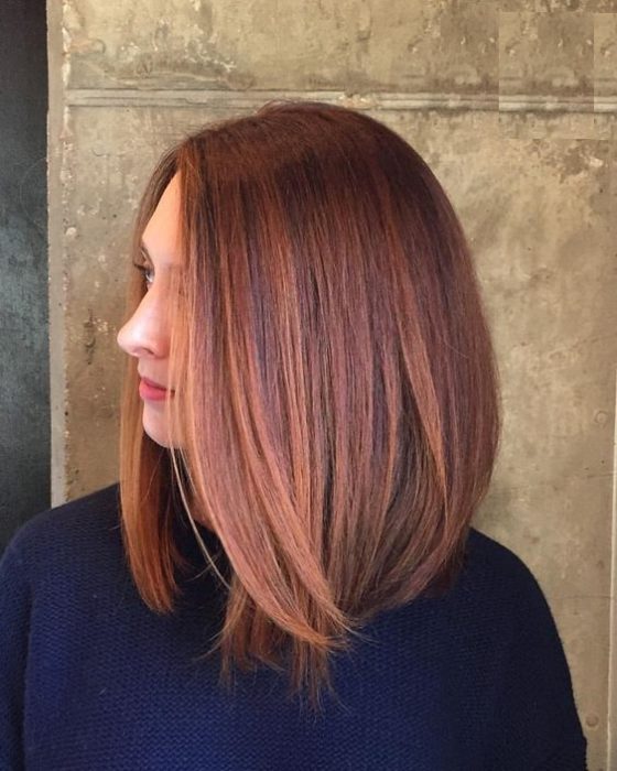 Chica con melena midi mostrando su cabello castaño deocrado con mechones peachy copper