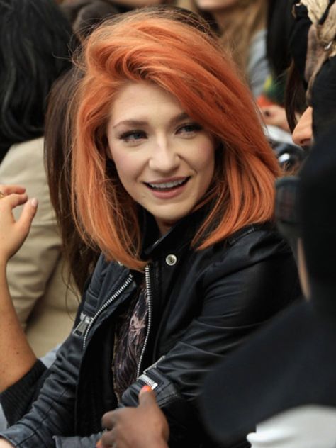 Chica con chaqueta negra, sonriendo, mostrando su cabello teñido en peachy copper