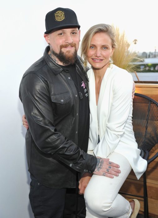 Cameron Diaz y Benji Madden abrazados mientras están sentados en una terraza 