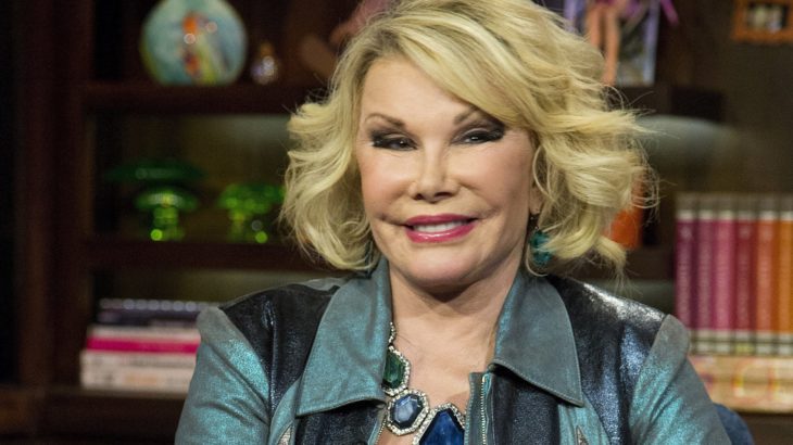 Joan Rivers usando una blusa de color verde mientras está sentada delante de un librero 