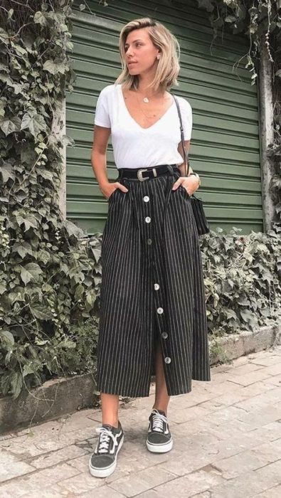 Chica rubia de pelo corto con blusa blanca y falda midi negra