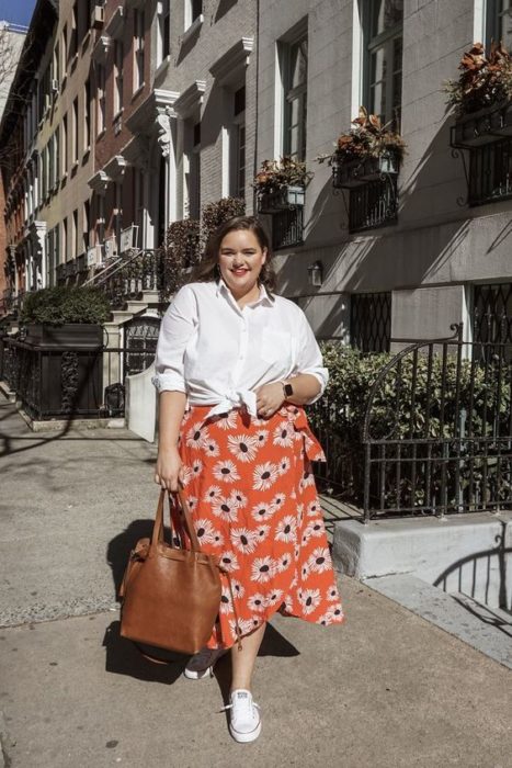 Chica curvy con camisa blanca y falda floreada roja y tenis blancos