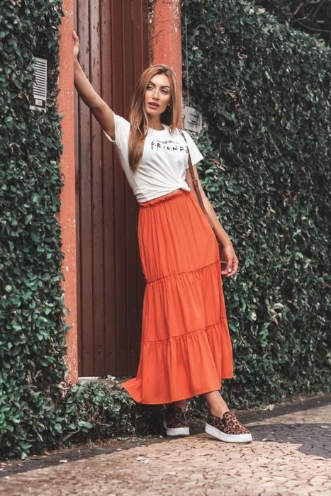 Chica alta y delgada con blusa blanca y blusa midi naranja