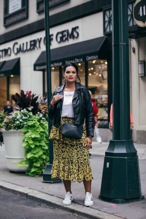 Chica morena con chaqueta de cuero, blusa blanca y falda midi amarillo con negro