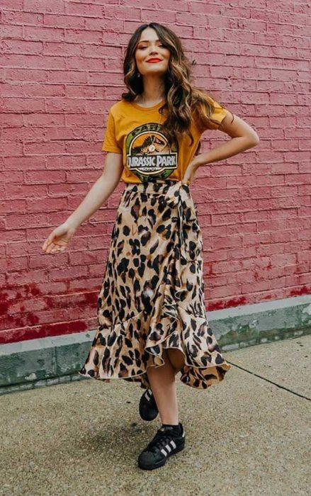 Chica de cabello castaño largo con blusa amarilla y falda midi de leopard print y tenis negros