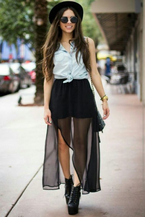 Chica llevando outfit con falda negra a transparencias, camisa de mezclilla y sombrero