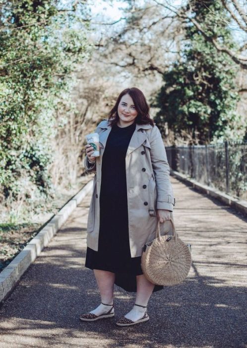 Mujer plus size con gabardina beige y vestido negro con bolso circular tipo canasta