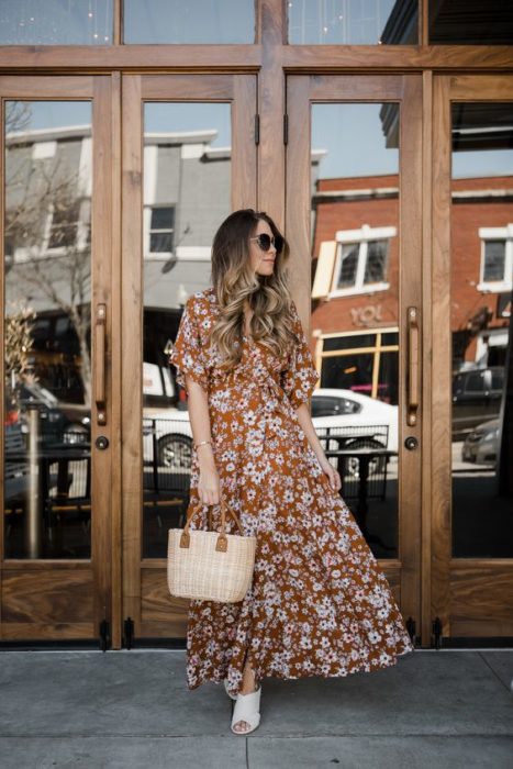 Mujer de cabello largo castaño con vestido de flores largo y bolsa tipo canasta