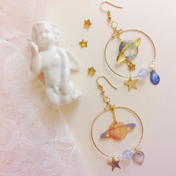 Aretes inspirados en el universo color dorado, con saturno en ellos