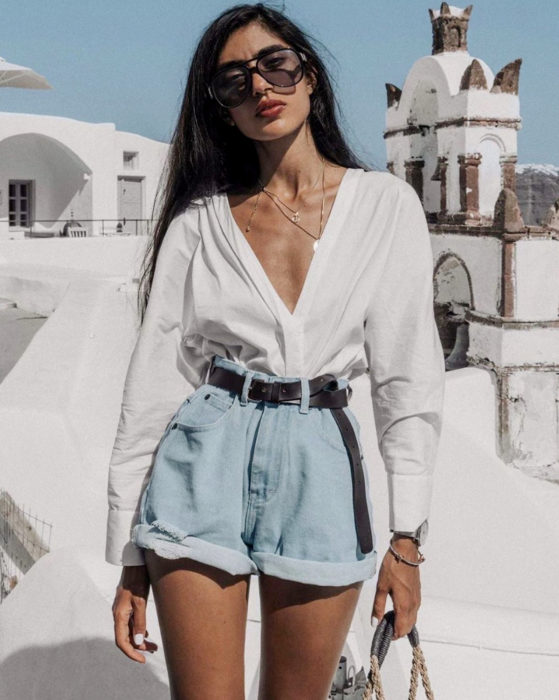 Looks con short vintage; mujer con blusa blanca de vestid, cabello negro lacio y largo, lentes de sol