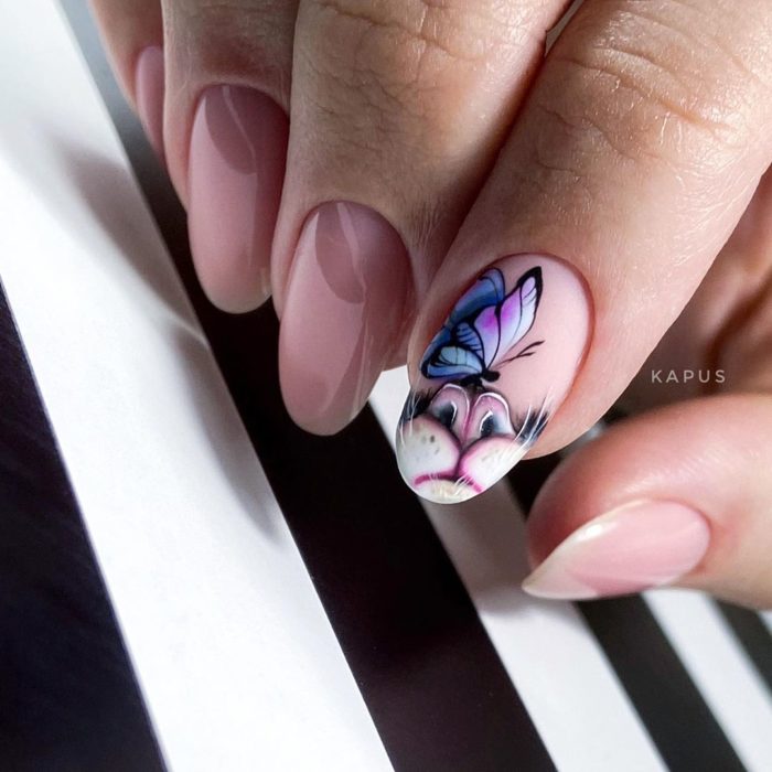 Manicura en forma de almendra en colores rosa y con decorado de una mariposa en morado