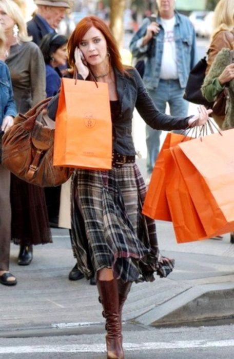 Escena de la película El Diablo Viste a la moda. Emily camiando por la calle sosteniendo varias bolsas en las manos 