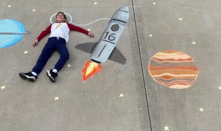 Dibujo de hecho con tiza de un niños sobrevolando el espacio 