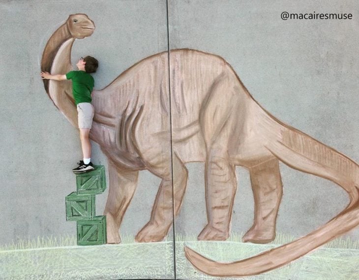 Dibujo de hecho con tiza de un niño saludando a un dinosaurio cuello largo