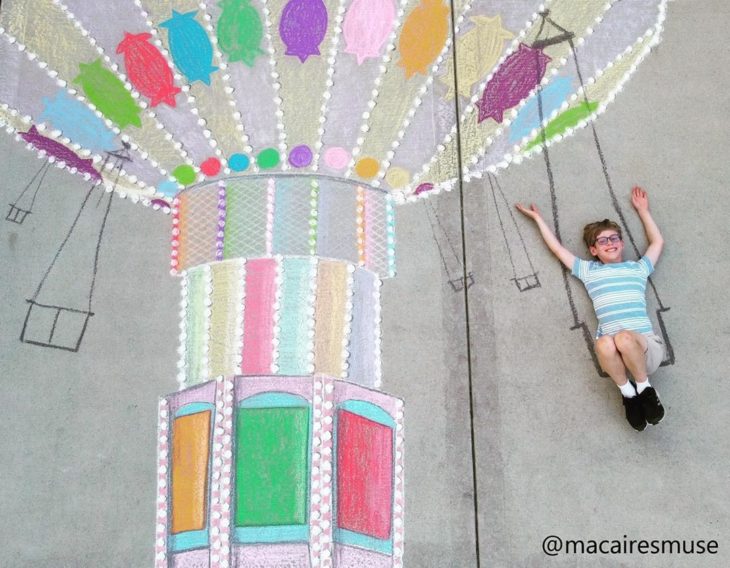 Dibujo de hecho con tiza de un niño paseando en un juego de feria similar a los columpios eléctricos