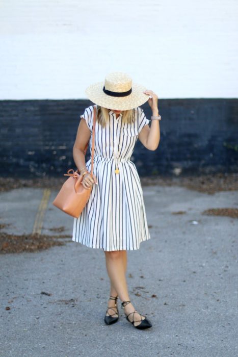 Chica usando vestido de rayas con sombrero y bucket bag color camel