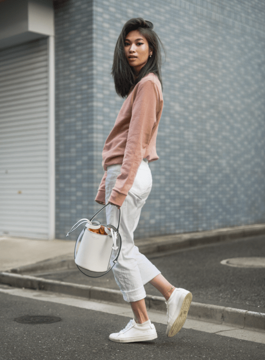 chica usando jeans capri blancos, con sudadera rosa, y bucket bag blanca