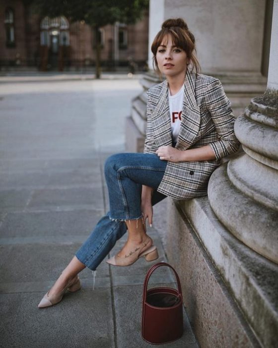 Chica usando jeans con playera blanca, blazer de estampado a cuadrosy bucket bag color café